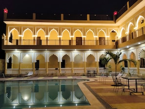 A hotel with a pool, outdoor seating, and traditional architectural design.