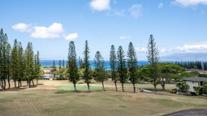A golf course with a view of the ocean and a house in the background. - 🏝️ Maui is Calling - Beautiful Kapalua Ocean and Golf Course View (Lahaina)