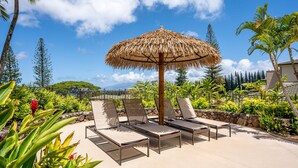 A poolside area with lounge chairs, a thatched umbrella, and tropical plants. - 🏝️ Maui is Calling - Beautiful Kapalua Ocean and Golf Course View (Lahaina)