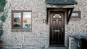 Un bâtiment en briques avec une porte brun foncé portant le numéro 21, une fenêtre et une petite boîte aux lettres.