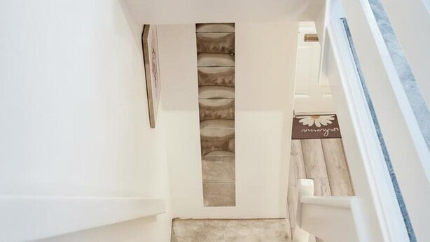 Un intérieur moderne avec un long couloir, des colonnes en béton et un escalier agrémenté de touches de bleu.
