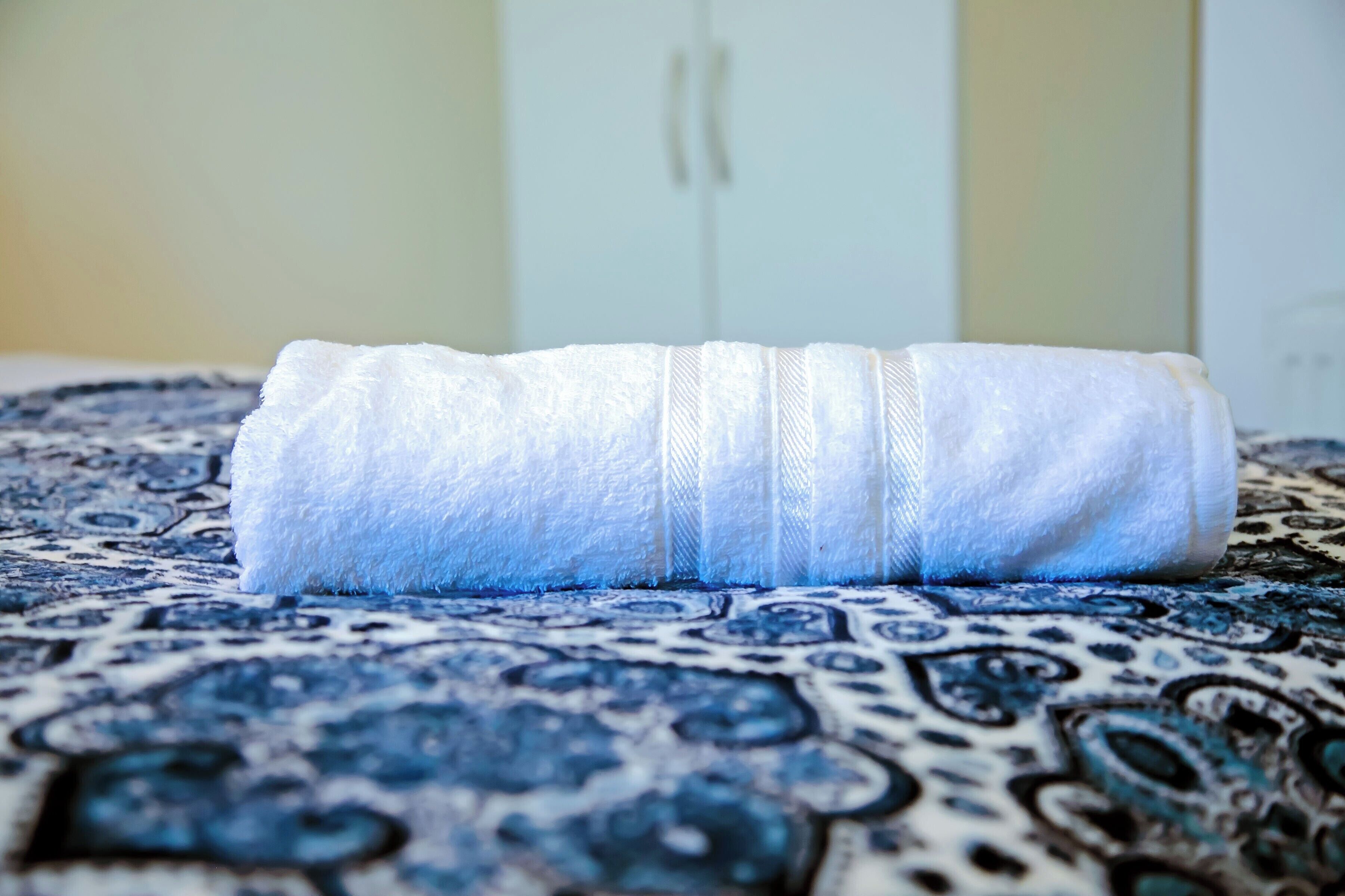 A rolled-up white towel on a patterned blue and white carpet.
