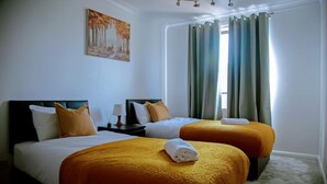 Une chambre d’hôtel avec deux lits, un tableau au mur et une fenêtre avec des rideaux.
