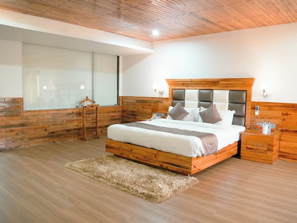 A bedroom with a wooden headboard, a large window, a bedside table, and a fluffy rug.
