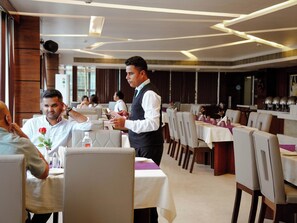 A restaurant interior with tables, chairs, and a waiter. - Donyi Polo International Hotel (Itanagar)