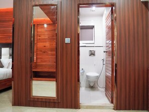 A room with a wooden panel design, a bed, a bathroom with a toilet and shower, and a mirror. - Donyi Polo International Hotel (Itanagar)