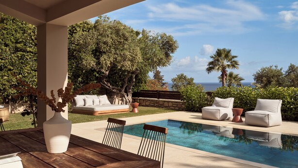 Un espace aménagé au bord de la piscine, avec une table en bois, des chaises et un ensemble de canapés.