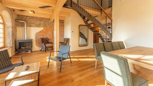 A spacious living area with a wooden floor, a fireplace, a staircase, and a dining table. - HexenburgbeiDresden 4 Zimmer Architektengaleriewohnung mit Whirlwanne, Kamin und Balkon - Nähe Sächsische Schweiz (Großharthau)