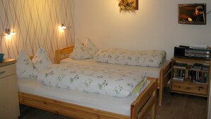Een slaapkamer met een houten bed, een tv aan de muur en een nachtkastje met een lamp.