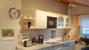 Een moderne keuken met witte kastjes, een inbouwmagnetron en een koffiezetapparaat.