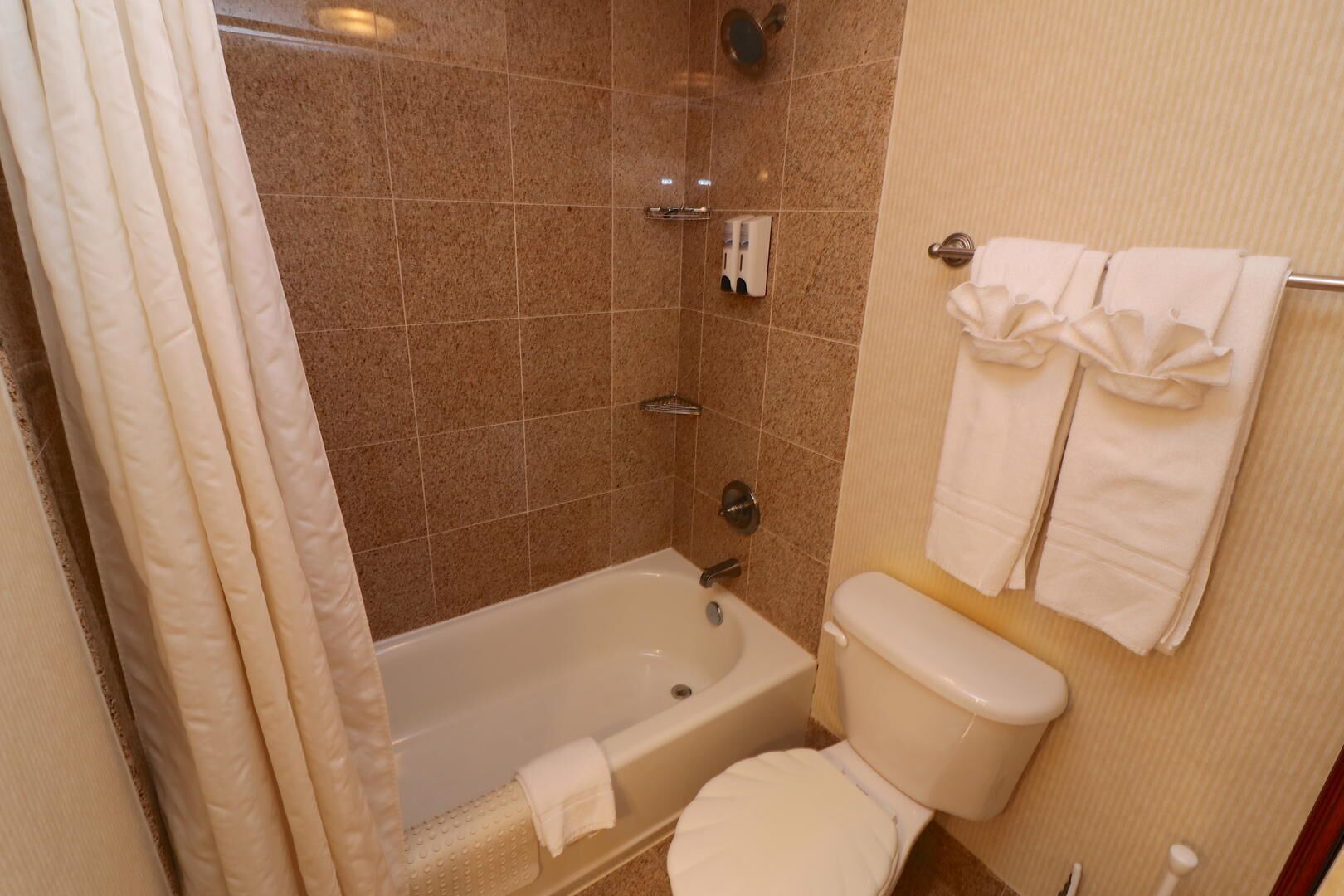 Een badkamer met een bad, toilet en een handdoekrek met handdoeken.