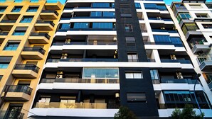 A multi-story building with balconies, large windows, and air conditioning units.