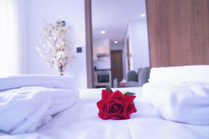 A neatly made bed with white linens and a red rose in the center. - Charming 1-bedroom apartment near Train Station in amazing Casablanca with AC (Casablanca)