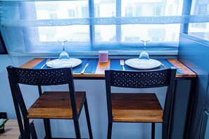 A dining table with two chairs, a pair of wine glasses, a fork, a knife, and a small decorative item. - Charming 1-bedroom apartment near Train Station in amazing Casablanca with AC (Casablanca)