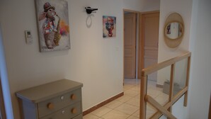 Un passadís amb una escala de fusta, un taulell beig i dos quadres a la paret.