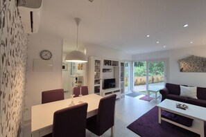 A modern living room with a dining area, a television, and a sofa.