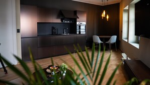 Una cucina moderna con mobili scuri, forno integrato e zona pranzo con due sedie bianche.