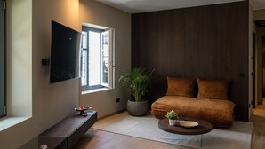 Un soggiorno moderno con un divano, un tavolino, una televisione, una pianta in vaso e una finestra.