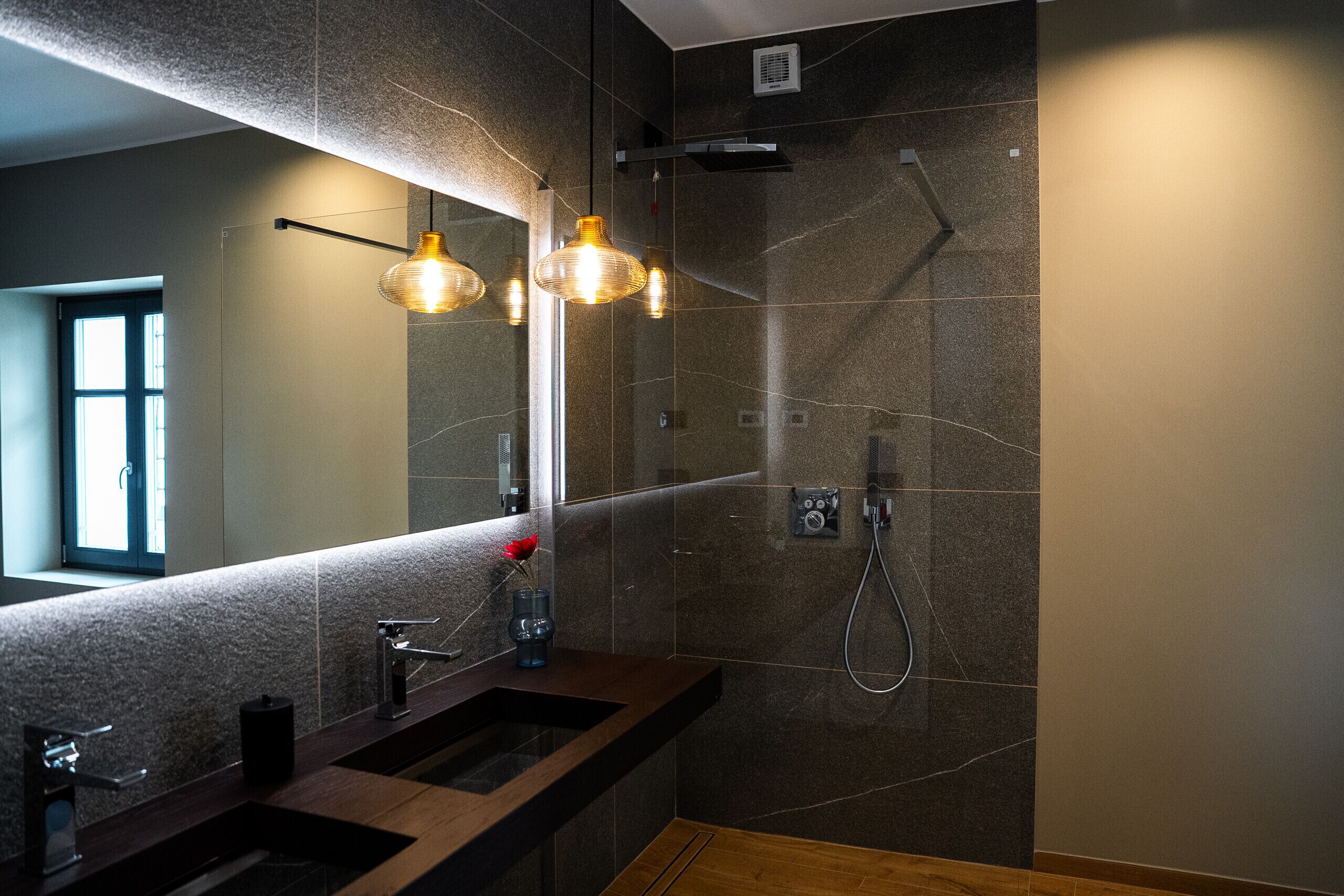 A modern bathroom with a large mirror, dual sinks, and a shower.