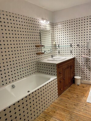 A bathroom with a bathtub, wooden vanity, and a shower area. - Old town house at the foot of the castle (Azay-le-Rideau)