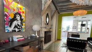 Een moderne woonkamer met een open haard, een eethoek met een zwarte bank, en een levendig kunstwerk aan de muur.