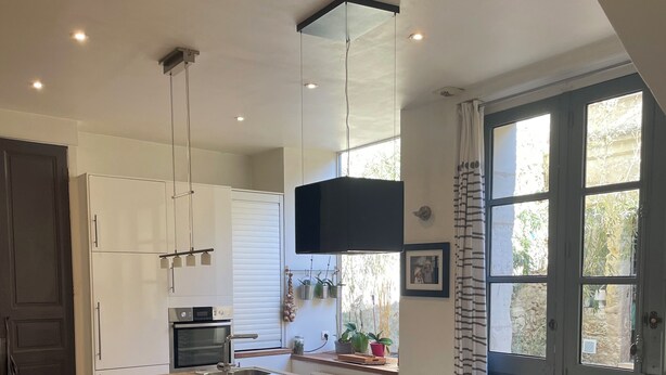 Een moderne keuken met een centraal eiland, witte kastjes en een groot raam voor natuurlijk licht.