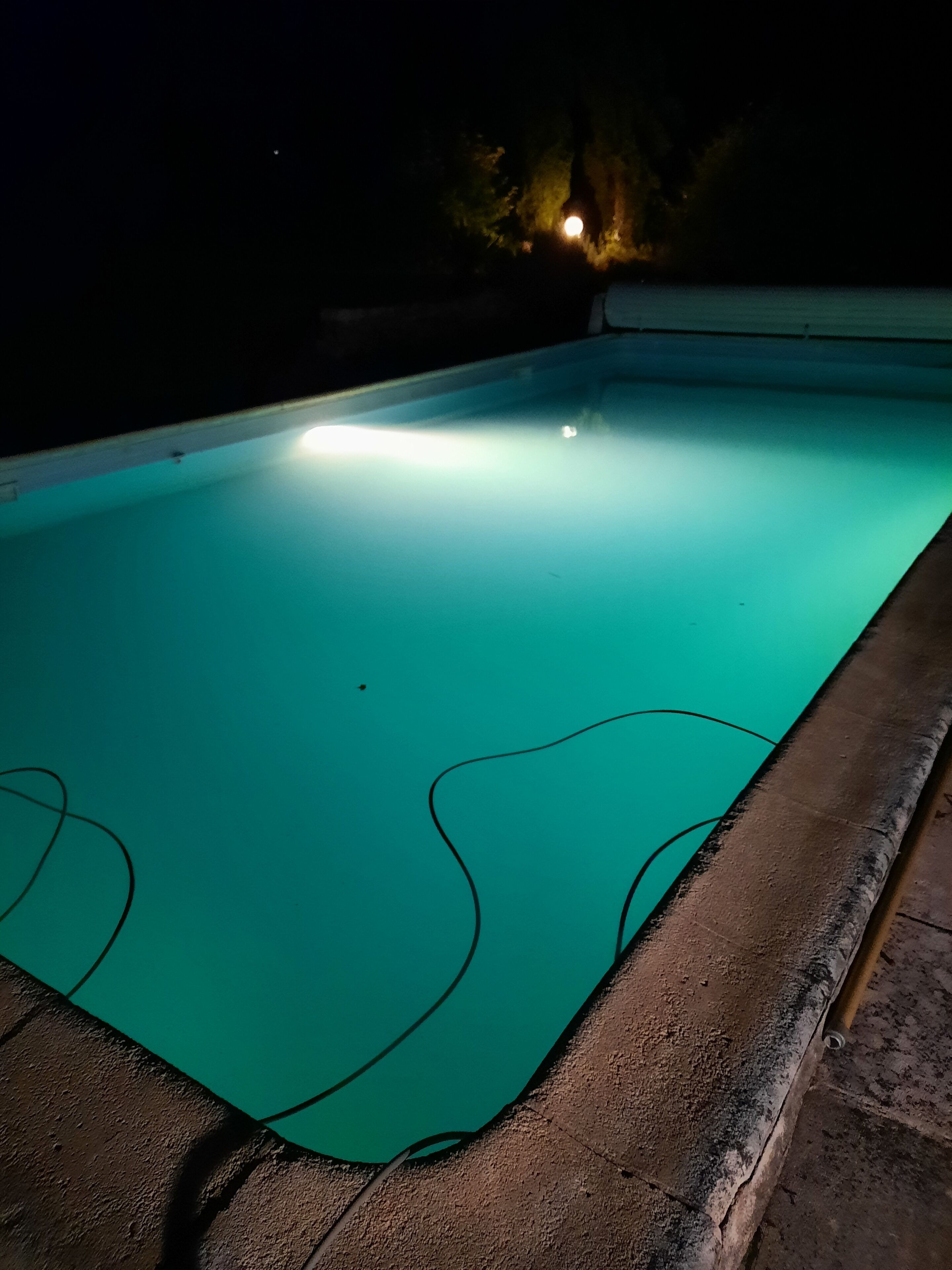En swimmingpool om natten med en lyskilde i den anden ende.