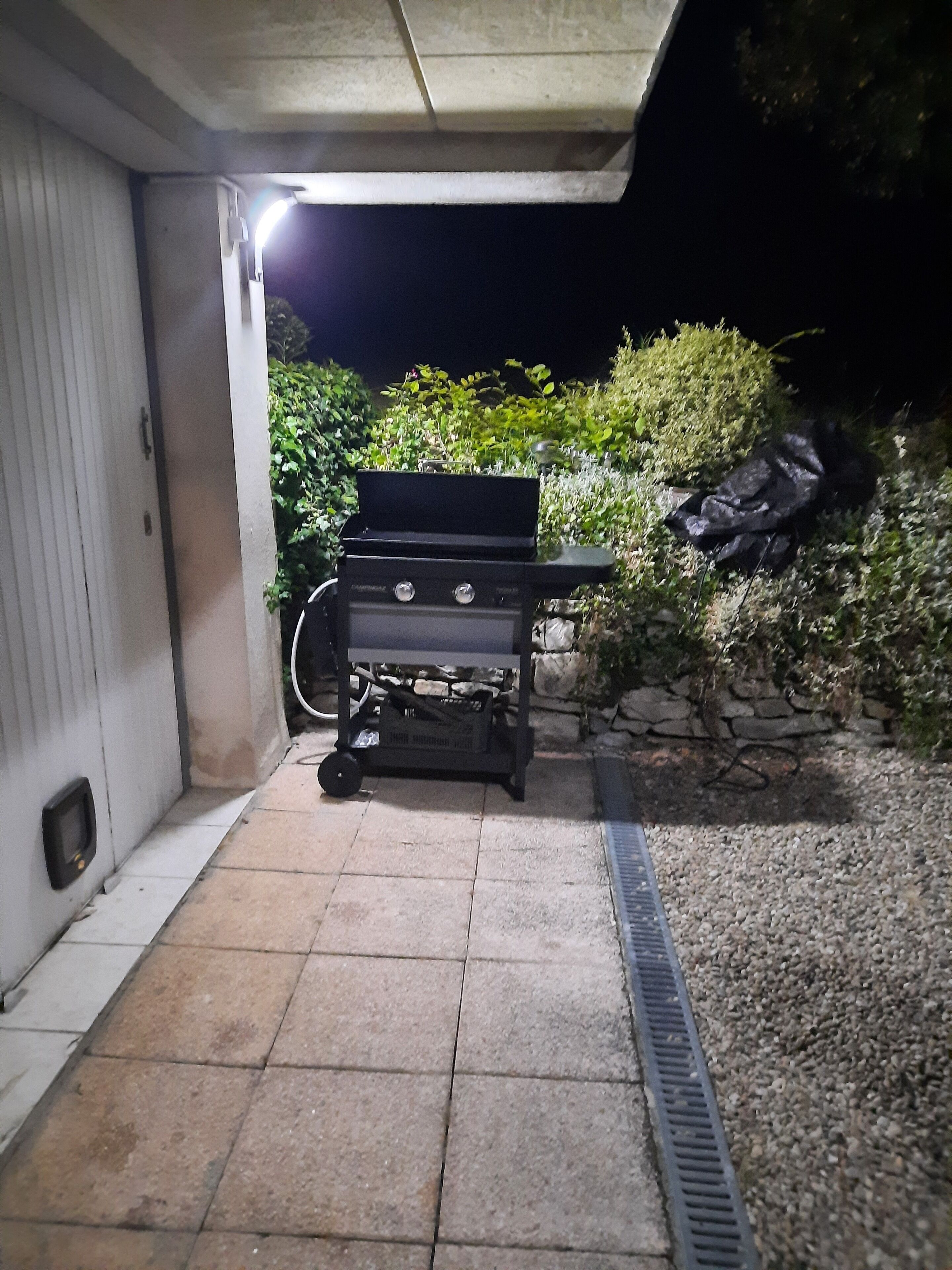 Ulkona, rakennuksen vieressä, on grilli ja sen yhteydessä laatoitettu terassi.