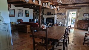 Uma sala de jantar ampla, com uma grande mesa de madeira e cadeiras, cercada por estantes de livros e uma lareira.
