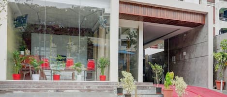 A modern building with a glass entrance, potted plants, and a red awning.