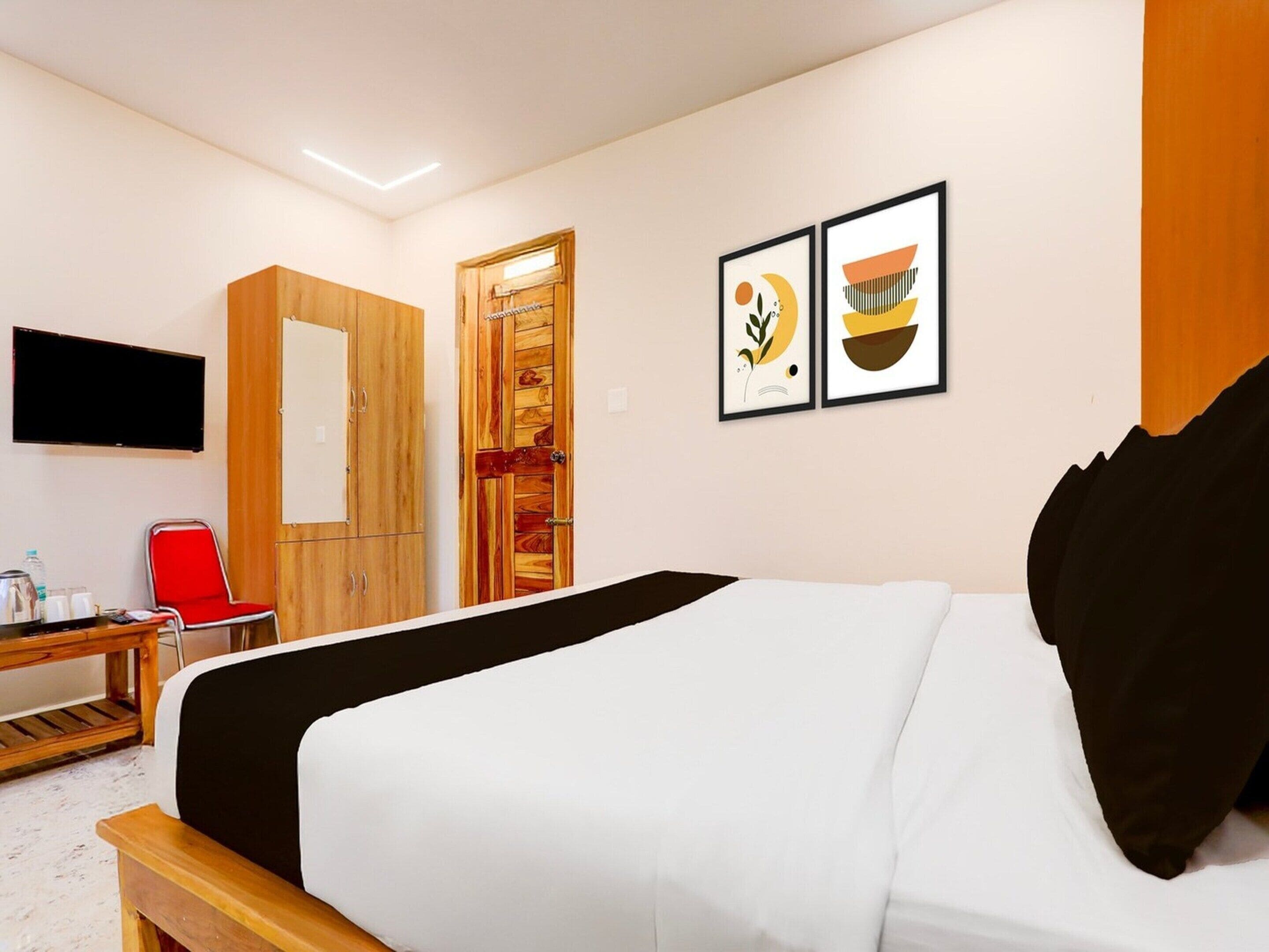 Una habitación de hotel con una cama, un escritorio con silla, un televisor y una puerta.