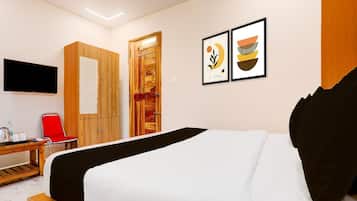 Una habitación de hotel con una cama, un escritorio con silla, un televisor y una puerta.