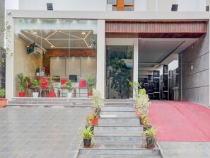 A modern building with a glass entrance, red chairs outside, and potted plants on the steps. - Townhouse Sri Padmavati Ammavaari Temple (Tirupati)