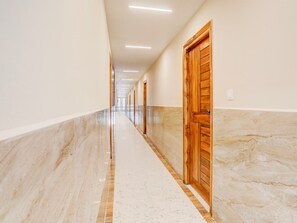 A long, narrow hallway with marble flooring, wooden doors, and recessed ceiling lighting. - Townhouse Sri Padmavati Ammavaari Temple (Tirupati)
