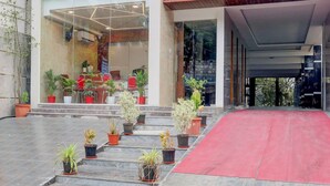 A modern building with a glass entrance, potted plants, and a red carpet leading to the entrance. - Townhouse Sri Padmavati Ammavaari Temple (Tirupati)