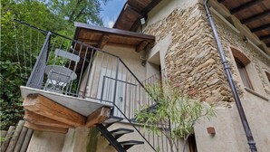 Ein Gebäude aus Stein mit einem hölzernen Balkon, einer Metalltreppe und einem kleinen Fenster.