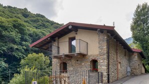 A stone building with a balcony, a concrete platform, and a no parking sign. - Faunet Apartment with Mountain View, Wi-Fi and Air Conditioning (Bernezzo)