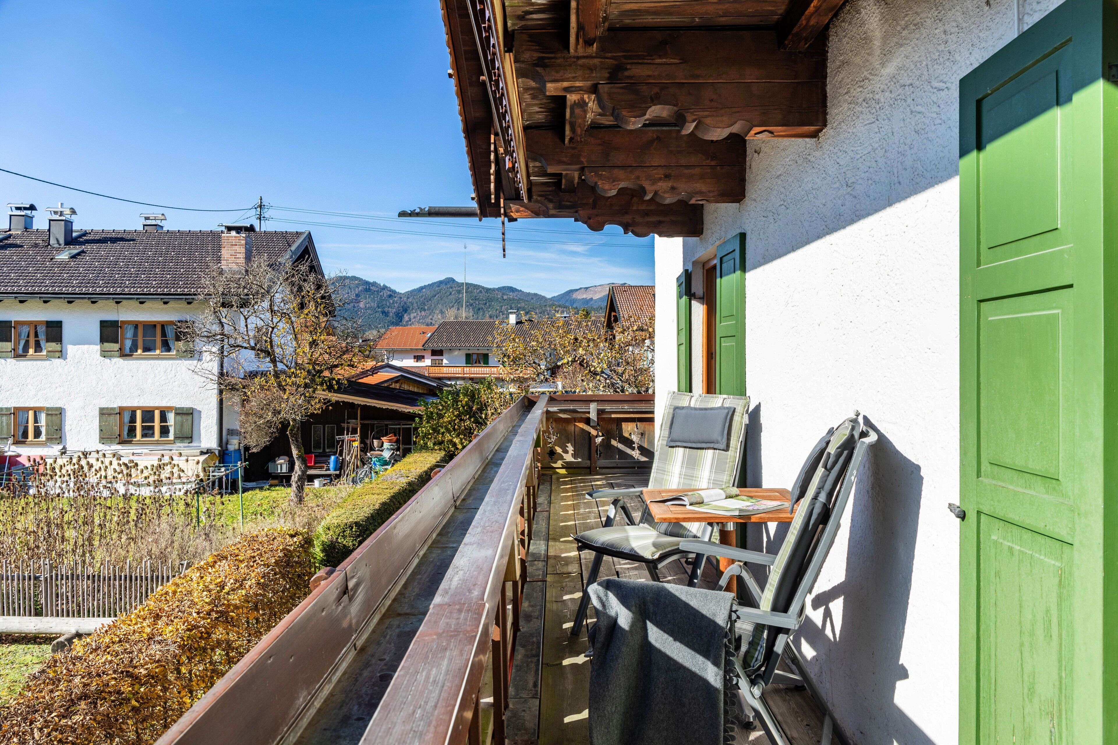 A balcony with a chair, a table, and a green door.