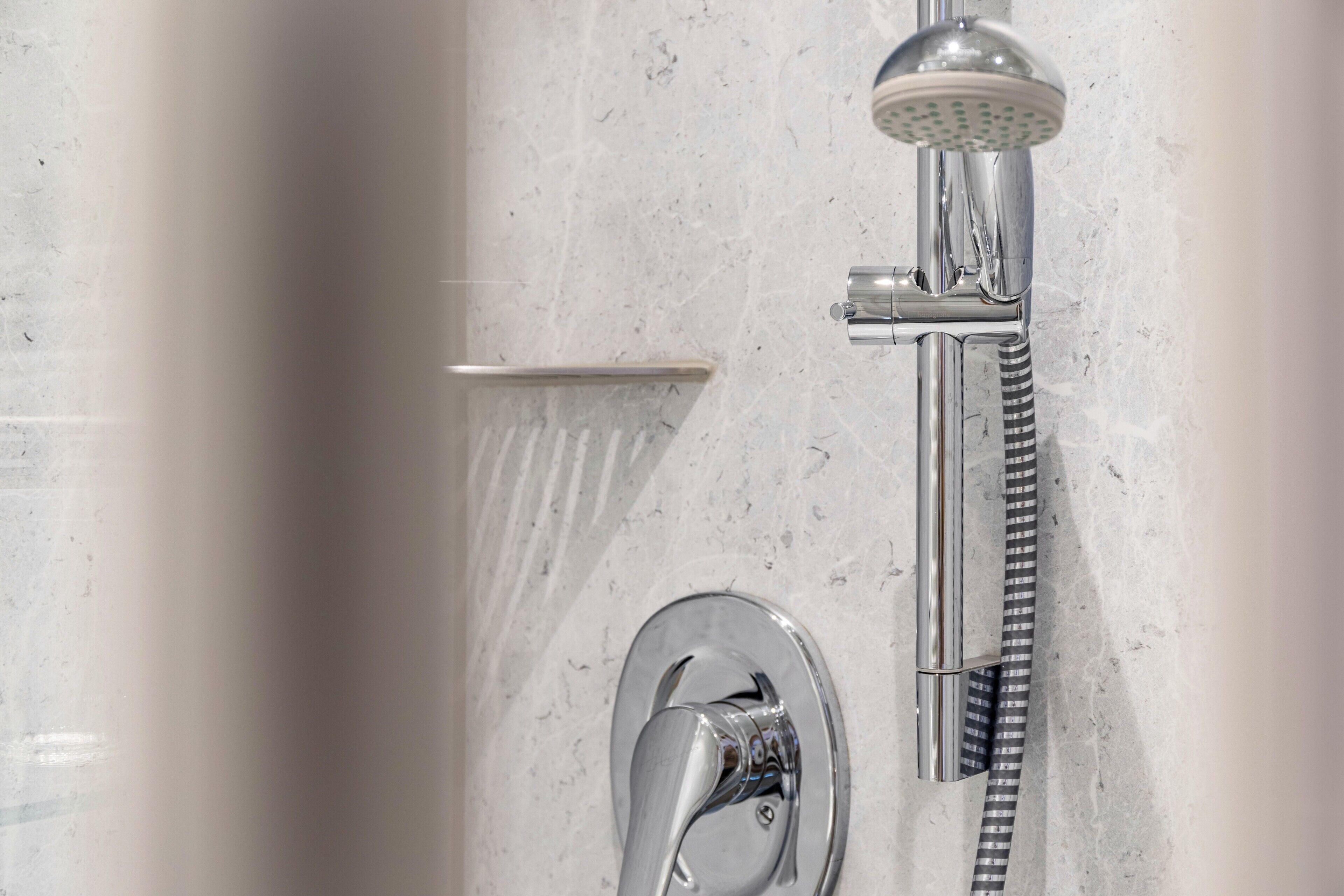 Eine Dusche mit Handbrause, Wandarmatur und flexiblen Duschschlauch.