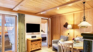 A wooden-paneled room with a television, a dining table with chairs, and a sofa. - Apartment '2' with Mountain View, Balcony and Wi-Fi (Krün)
