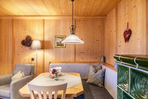 A wooden-paneled room with a table, chairs, a sofa, a lamp, a heart-shaped decoration, and a mirror on the wall.