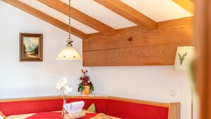 A dining area with a red cushioned bench, a wooden table, and a hanging light fixture.