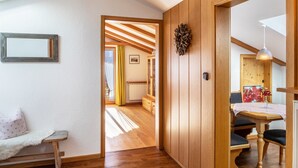 A room with wooden walls, a dining table with chairs, a bench, and a framed picture on the wall.