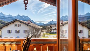 A mountain view from a wooden balcony with a rustic interior.