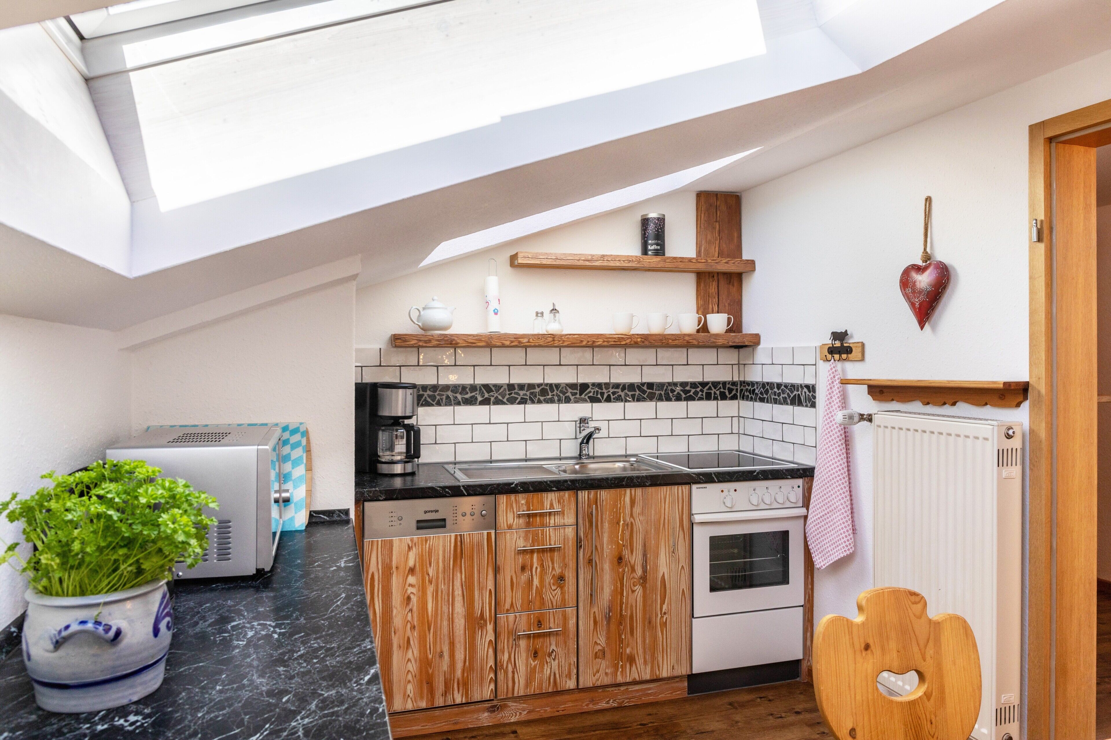 A compact kitchen with a skylight, built-in appliances, and a heart-shaped decoration.