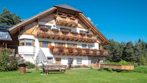 A multi-story building with balconies, a covered patio, and a garden area. - Apartment “Kardinerhof Bergwiese” with Mountain View, Shared Garden and Wi-Fi (Ritten)