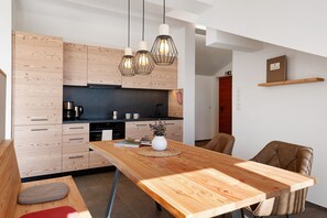A modern kitchen with wooden cabinets, a black countertop, and pendant lights.