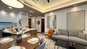 A modern living room with a sofa, a dining table set for four, and a kitchen area in the background. - Core Residence TRX Kuala Lumpur  (Kuala Lumpur)