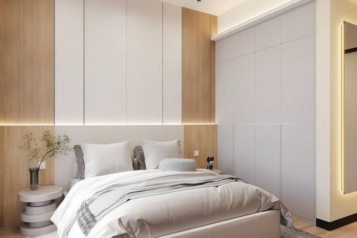 A modern bedroom with a large bed, a bedside table, and a wall-mounted light fixture.