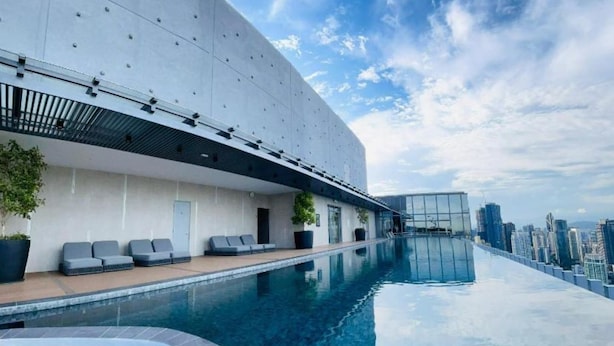 A modern building with a rooftop infinity pool, seating areas, and a city view. - Core Residence TRX Kuala Lumpur  (Kuala Lumpur)